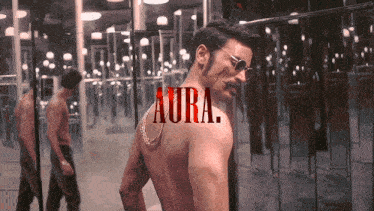 a man without a shirt is standing in front of a mirror with the word aura on his back