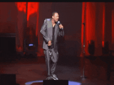 a man in a suit is singing into a microphone on stage