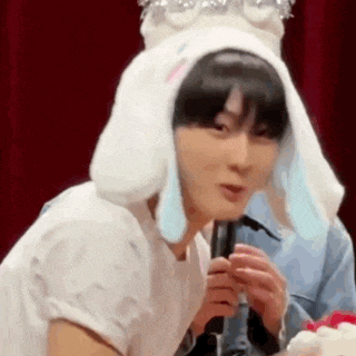 a young man wearing a bunny hat is holding a microphone .
