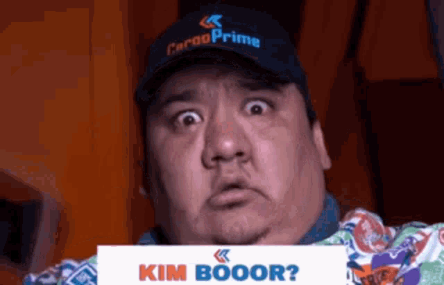a man in a cargo prime hat is holding a sign that says kim booor ?