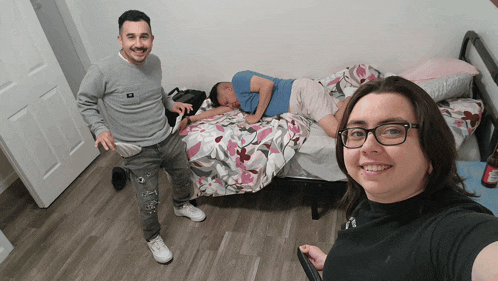 a man and a woman are standing next to a bed
