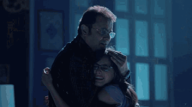 a man and woman are hugging a little girl in a living room