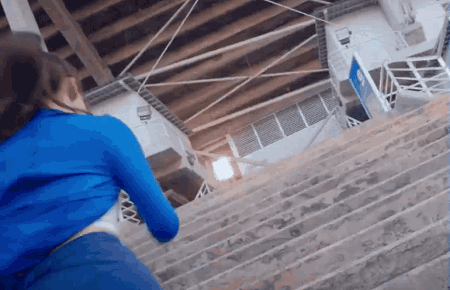 a woman in a blue shirt is running down stairs