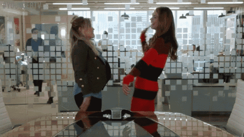 a woman in a red and black striped sweater stands next to a woman in a green jacket