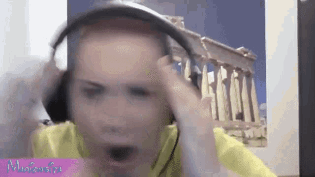 a man wearing headphones and a yellow shirt is making a funny face .