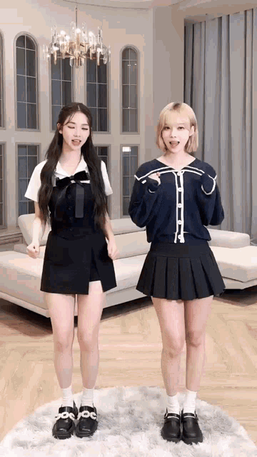 two girls are standing next to each other in front of a couch