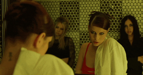 a woman in a white shirt is looking at her reflection in a mirror