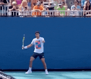 a man holding a tennis racquet on a tennis court in front of a crowd