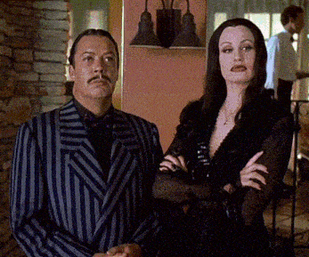 a man in a striped suit and a woman in a black dress stand next to each other