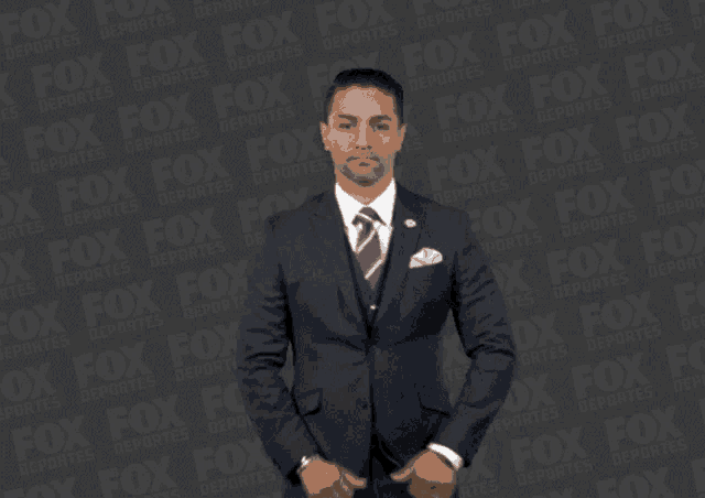 a man in a suit and tie is standing in front of a fox logo