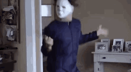 a person wearing a white mask is dancing in a room .