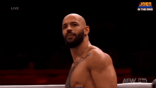 a man with a beard is standing in a boxing ring with a tbs logo in the background .