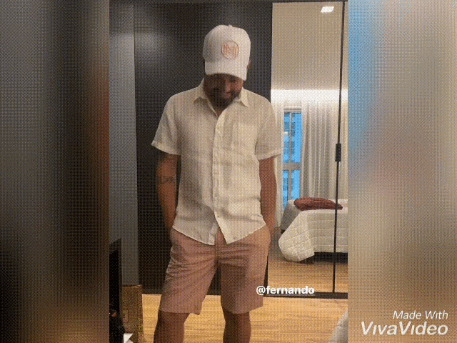 a man is standing in front of a mirror wearing a white shirt and a white hat