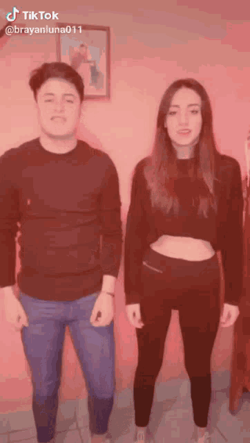 a man and a woman are standing next to each other in front of a pink wall with tiktok written on the bottom of the screen