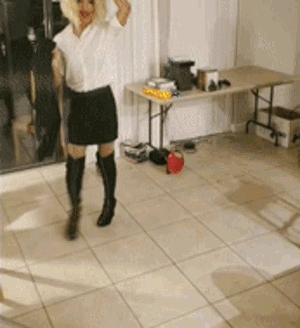 a woman in a white shirt and black skirt is standing in a room