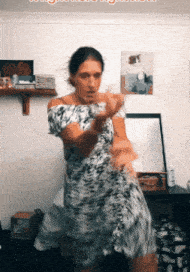 a woman in a leopard print dress is dancing in front of a wall that has a picture of a cat on it