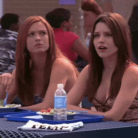 two girls sit at a table with a bottle of aquafina water
