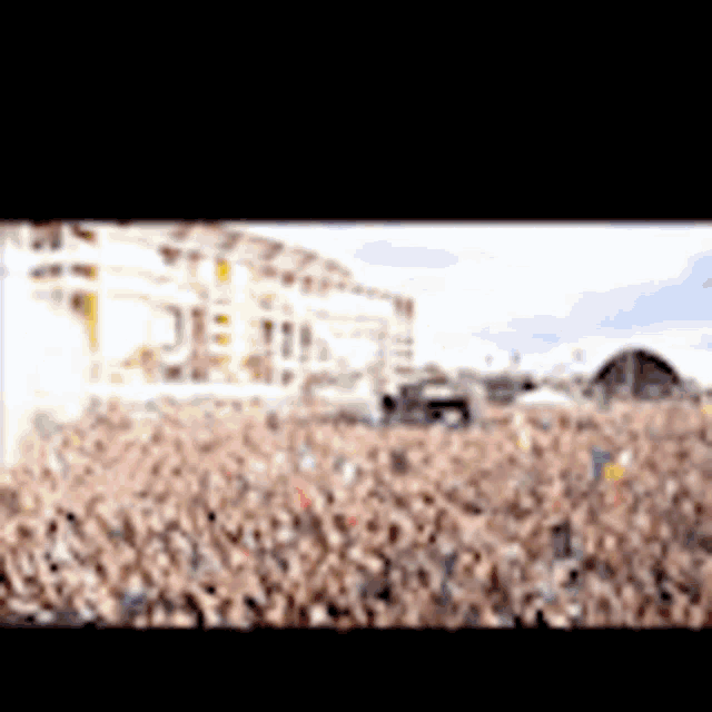 a large crowd of people are gathered in a field at a concert
