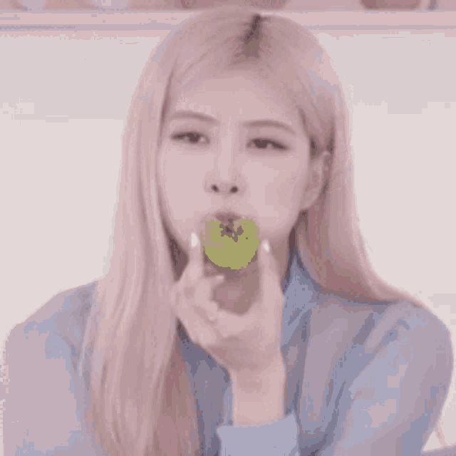 a woman with pink hair is holding a green apple in her hand .