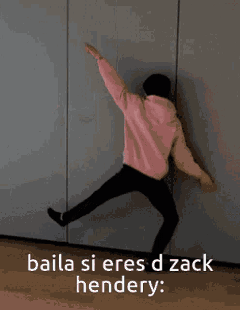 a person in a pink hoodie is dancing with the words baila si eres d zack hendery behind them
