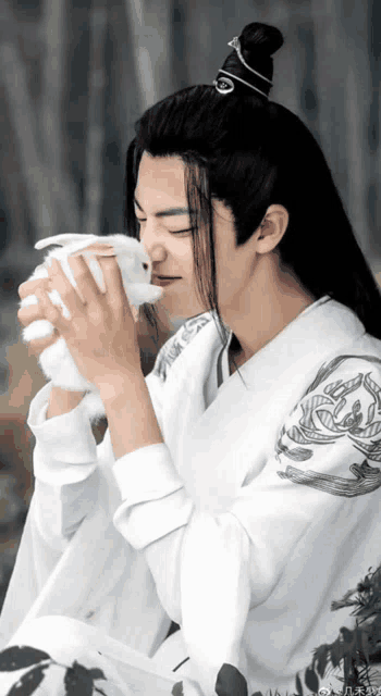 a man with long hair is holding a stuffed rabbit in his hands