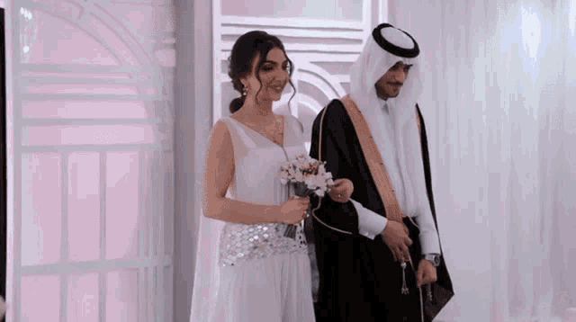 a bride and groom pose for a picture in front of a pink curtain