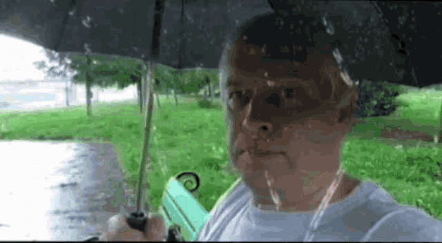 a man is holding an umbrella in the rain while sitting on a bench