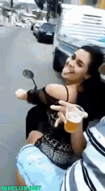 a woman is sitting on a man 's lap holding a glass of beer and smiling ..