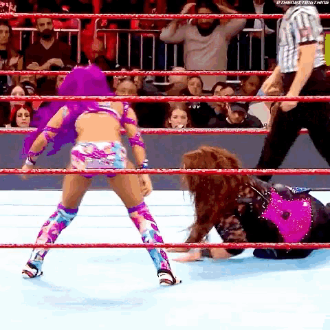 two women are wrestling in a wrestling ring with a referee watching .