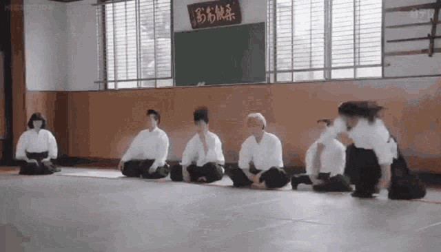 a group of people are sitting on the floor in a gym with a sign on the wall that says ' samurai '