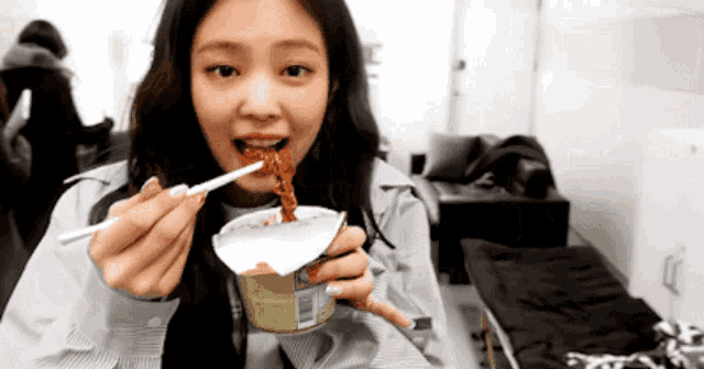 a woman is eating something from a can with chopsticks