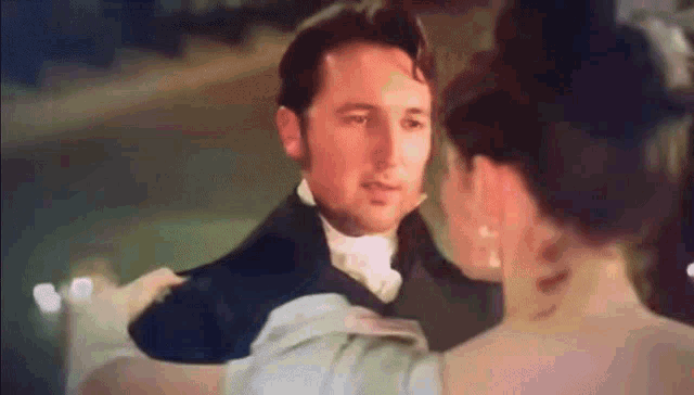 a man and woman are dancing together in a ballroom .