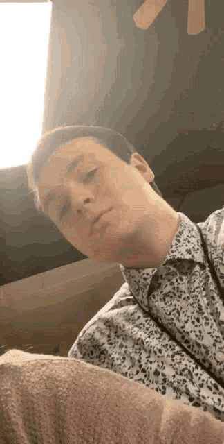 a man in a leopard print shirt looks at the camera with his eyes closed