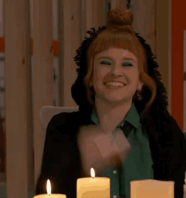 a woman in a green shirt is sitting at a table with candles .