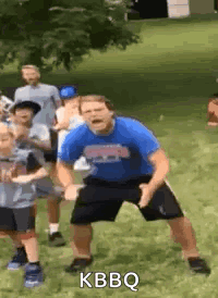 a man in a blue shirt and black shorts is dancing in a field with a group of children .