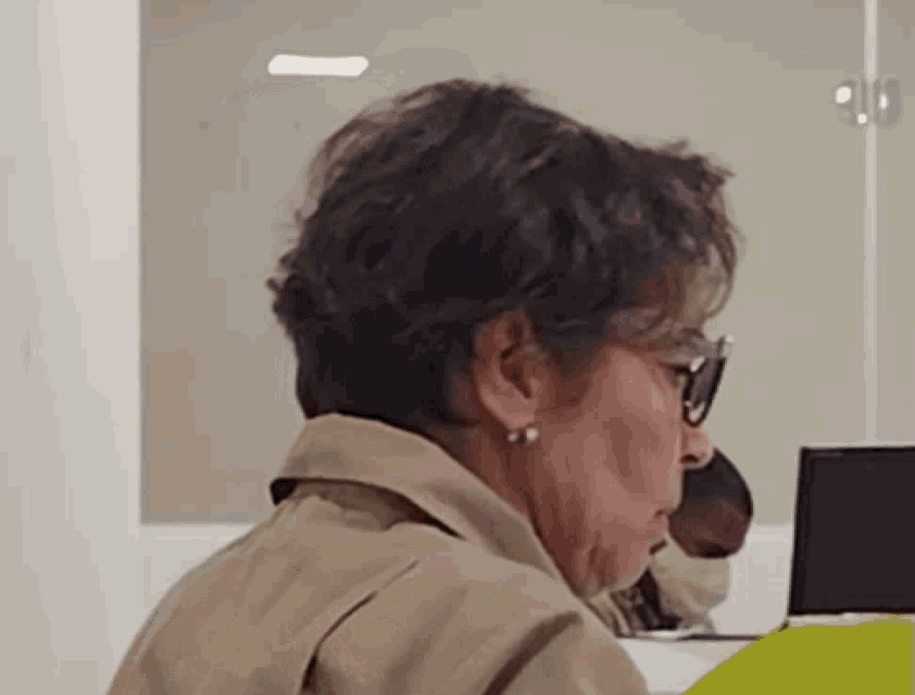 a woman wearing glasses and earrings is looking down at something