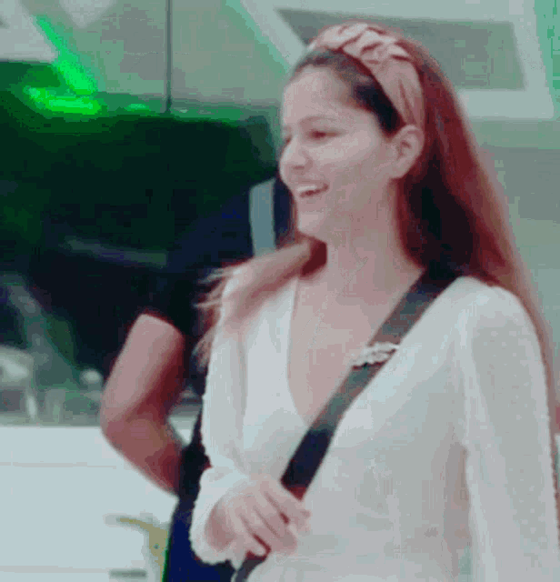 a woman wearing a headband and a white shirt smiles for the camera