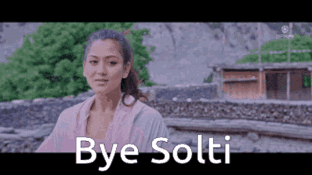 a woman in a pink shirt is standing in front of a building with the words `` bye solti '' written on the bottom