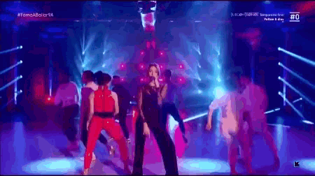 a woman singing into a microphone on a stage with the number 0 on the bottom right