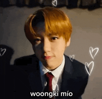 a young man in a suit and tie is looking at the camera with hearts flying around him .