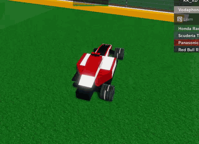 a red white and black race car is driving on the grass