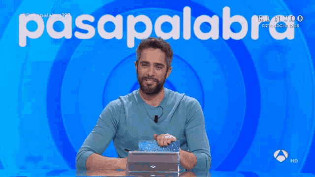 a man sitting in front of a blue background with the word pasapalabra