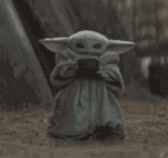 the child from star wars is drinking a cup of coffee .