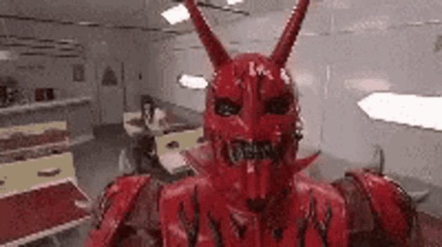 a red robot with horns is standing in a room in a restaurant .