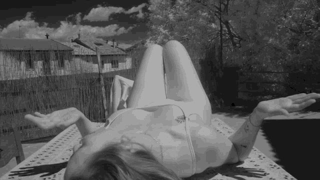 a black and white photo of a woman laying on a blanket