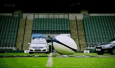 a police car is driving past a large ball on a soccer field