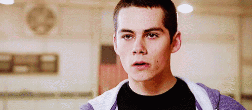 a young man is standing in a gym wearing a purple hoodie and a black shirt .