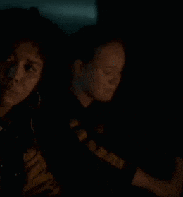 two people are sitting in a dark room looking at something .
