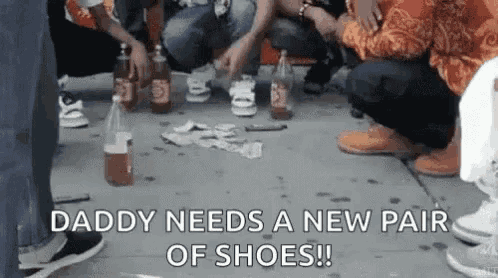a group of people are sitting on the sidewalk with bottles of beer and money on the ground .