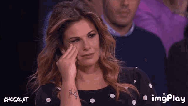 a woman with a tattoo on her wrist is crying in front of a shocklat logo